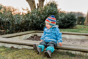 Toddler sitting on sandbox