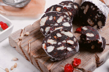 Chocolate sausage made of cookies, cocoa powder, nuts and dried berries with sugar powder. Dessert of Russian, Italian and Portuguese cuisines