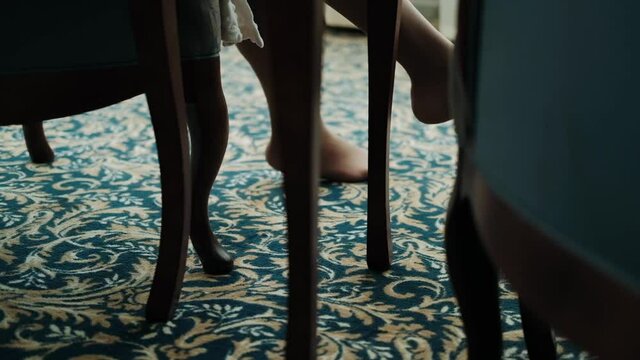 Female legs in beige pantyhose and shoes on dark background