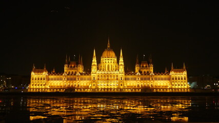 Fototapeta premium Parliament building by night in Budapest. with reflection in the icy river Danube