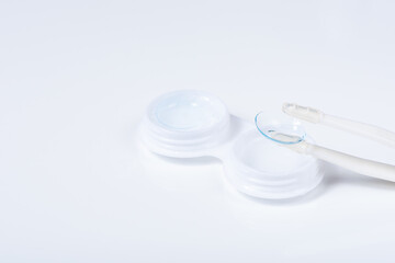 Soft contact lenses with solution, container and tweezers on white background with place for text. Macro photography
