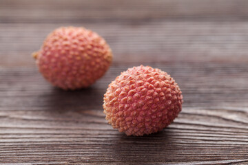 two lychees on a dark wooden table