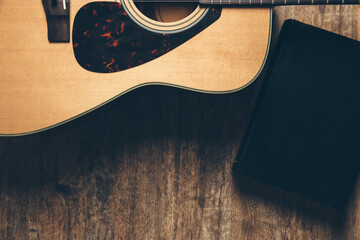 A guitar and a bible on a wooden background in a dimly lit environment. Soft light and worship