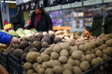 Soft focused shot of vegetable department in grocery store, supermarket, mall, hypermarket or shopping center. Boxes with beetroot and potatoes, unrecognizable people on background. Healthy eating.
