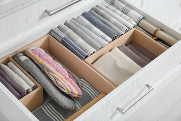 Fototapeta na wymiar Open drawer with different textiles in kitchen, above view