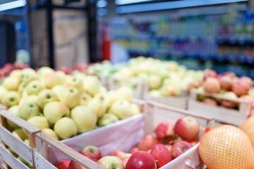 Soft focused shot of fruit department in grocery store, supermarket, mall, hypermarket or shopping center. Red, yellow and green apples in boxes. Healthy eating, avitaminosis  concept.