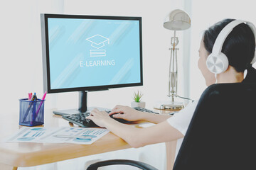 education online, e-learning. Young woman is sitting at table, working on computer monitor on screen e-learning and image of square academic cap, distance training