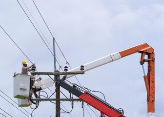 electrician works on bucket car to maintain high voltage transmission lines.