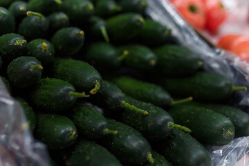 Soft focused shot of vegetable department in grocery store, supermarket, mall, hypermarket or shopping center. Boxes with tomatoes and cucumbers. Vegetarian healthy food concept.