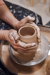 Women working on potters wheel making clay objects in pottery workshop