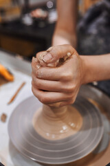 Women working on potters wheel making clay objects in pottery workshop
