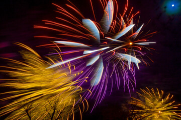 Bright fireworks and the moon in the dark sky