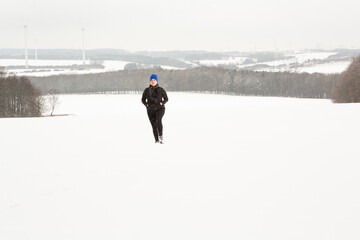 Lady walks in an open field while a heavy snow is falling