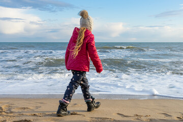 The child walks along the seashore