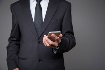 businessman in gray suit with mobile phone in hand on gray background