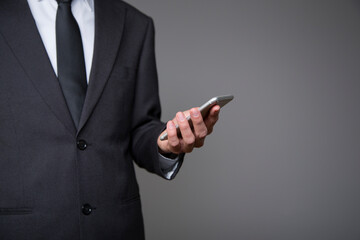 businessman in gray suit with mobile phone in hand on gray background