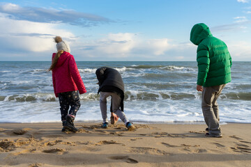 Children play on the seashore. The water surface is covered with waves