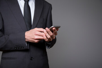 businessman in gray suit with mobile phone in hand on gray background