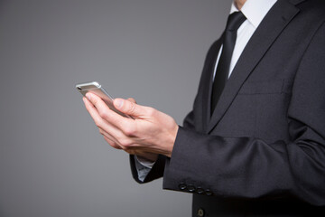 businessman in gray suit with mobile phone in hand on gray background