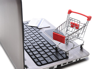 Internet, technology, ecommerce and online payment concept. Closeup of a shopping cart and credit cards on the keyboard of an open laptop computer.