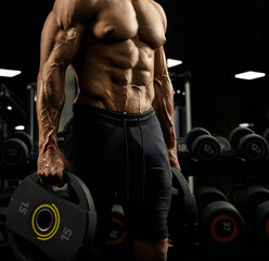 Tensed male bodybuilder holding weights.