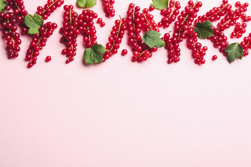 Delicious red currants and leaves on pink background, flat lay. Space for text