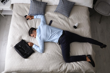 Exhausted businessman in office wear sleeping on bed at home after work, above view