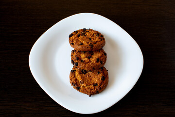 brown cookies in a white plate on a dark background
