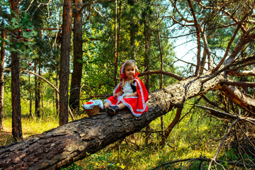 Fototapeta na wymiar girl in the forest in red clothes, Little Red Riding Hood, summer, green, park, young, tree, grass, beautiful, cosplay, path, path, trees, spring, heat, basket, book, wolf