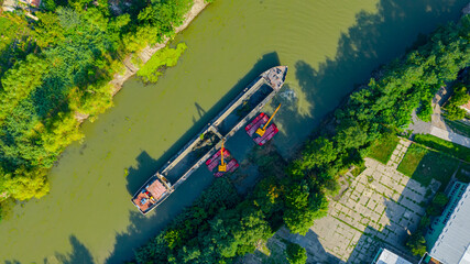 Aerial view of river, canal is being dredged by excavator