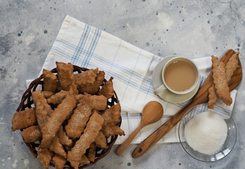 Natural wicker plate with ready made freshly baked cookies and a cup of coffee on a gray background with a kitchen napkin.Food background with homemade freshly baked cookies.