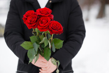 romantic young man with bouquet of red roses in hands, close-up