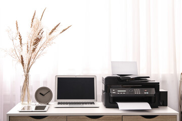 Modern printer, laptop and office supplies on white table indoors