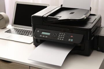 Modern printer and laptop on white table indoors