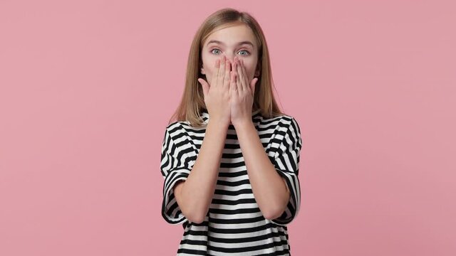 Charming pretty little blonde kid girl 12-13 years old in white black striped t-shirt isolated on pastel pink background studio. Childhood lifestyle concept. Looking aside blowing sending air kiss