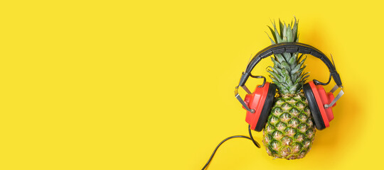 pineapple in red retro headphones on a yellow background