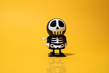 Halloween, plastic toy for children. Skeleton and skull, yellow background