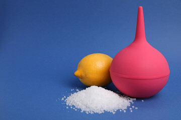 Enema, lemon and heap of salt on blue background, space for text. Medical treatment