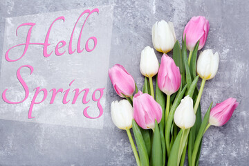 Bouquet of tulips with text Hello Spring on grey wooden table