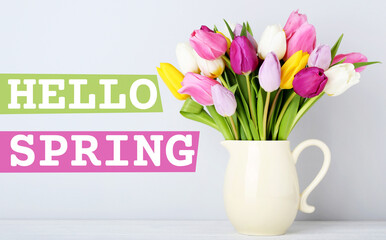 Bouquet of tulips in jug with text Hello Spring on wooden table
