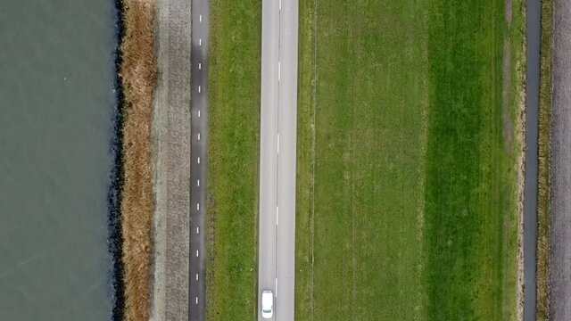 Overhead drone view on a levee with a road and a lake on the side. The levee is located on the shore of the Ketelmeer in Flevoland, The Netherlands