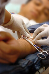 Unidentified medical staff with protective glove stick adhesive plaster on Asian man's arm after...