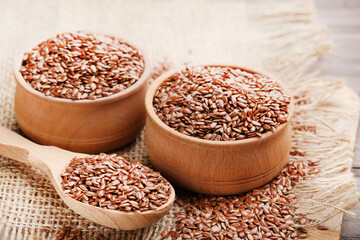 Flax seeds in bowls and spoon on brown burlap