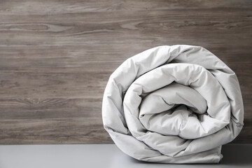 Soft rolled blanket on light grey table. Space for text