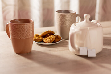 Biscuits, cups of tea and teapot on the table.