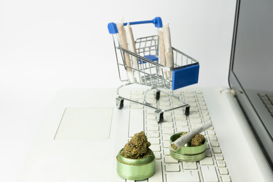 Marijuana buds on grinder with joints in shopping cart on laptop.Medical cannabis marijuana alternative medicine.Shopping online , weed store concept background.Mockup banner template with copy space