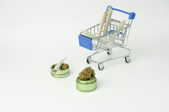 Marijuana buds on grinder with joints in shopping cart on white background.Medical cannabis marijuana alternative medicine.Shopping , weed store concept background.