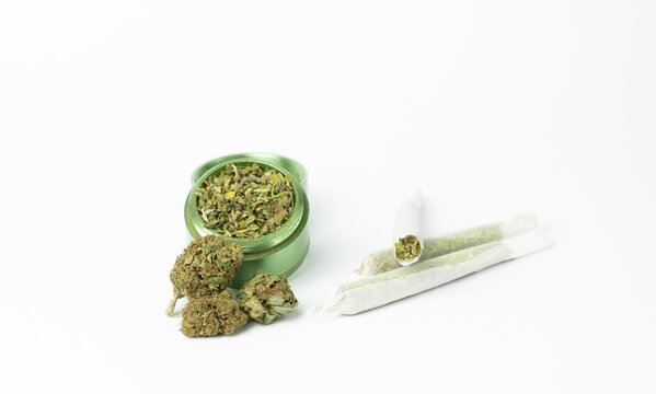 Buds of marijuana, grinder with crushed weed cannabis and rolled joints on white background.Medical and medicine concept.Selective focus with copy space.