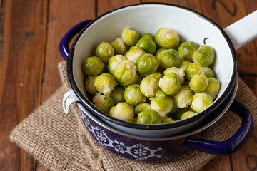 gekochter gr&uuml;ner Rosenkohl in Topf auf einem Tisch aus  braunem Holz in der K&uuml;che