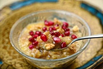 Ashure or Noah's pudding, the turkish dessert porridge in glass bowl on golden dish